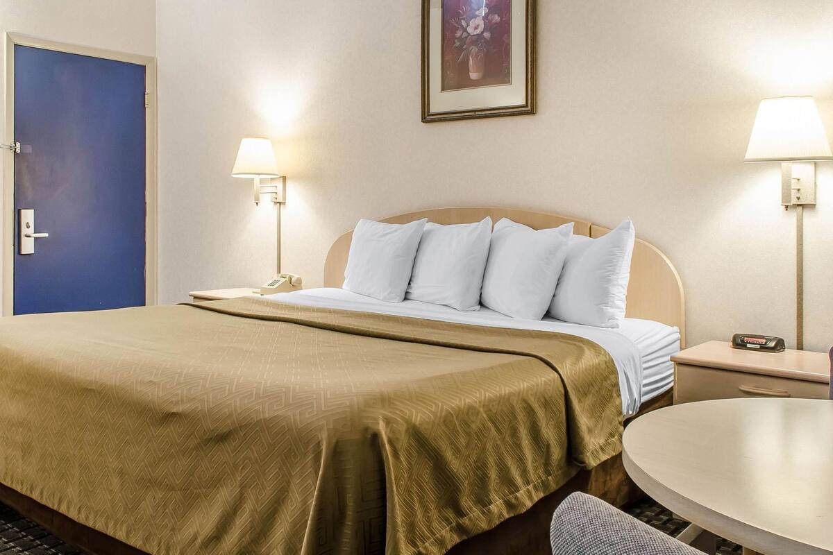 A hotel room with a bed, bedside lamps, a desk, and a chair.