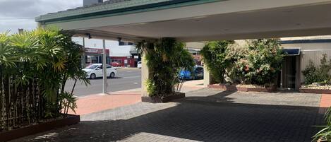 Een tankstation met een overdekte parkeerplaats, een rode auto en een blauwe auto er buiten.