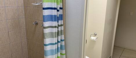 Un baño con cortina de ducha, inodoro y lavabo.