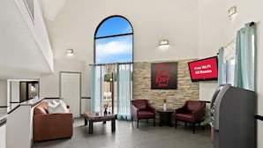 A modern hotel lobby with a large arched window, a Red Roof Inn sign, a flat-screen TV, and a self-service kiosk. - Red Roof Inn & Suites Duncan (Duncan)