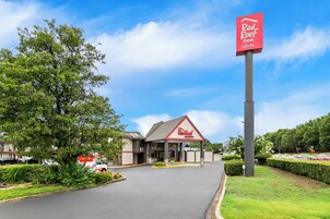 A Red Roof Inn & Suites with a clear sky, a well-maintained lawn, and a parking lot.