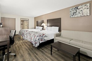 A hotel room with a large bed, a sofa, a desk with a chair, and a coffee machine. - Red Roof Inn & Suites Duncan (Duncan)