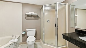 A bathroom with a glass-enclosed shower, a white toilet, a bathtub, and a black marble sink. - Red Roof Inn & Suites Duncan (Duncan)