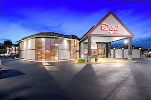 Um Red Roof Inn & Suites com um amplo estacionamento e uma entrada bem iluminada.