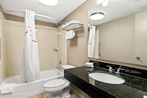 Un baño moderno con bañera, inodoro, lavabo y un espejo grande.