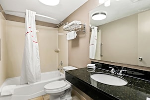 A modern bathroom with a bathtub, toilet, sink, and a large mirror.
