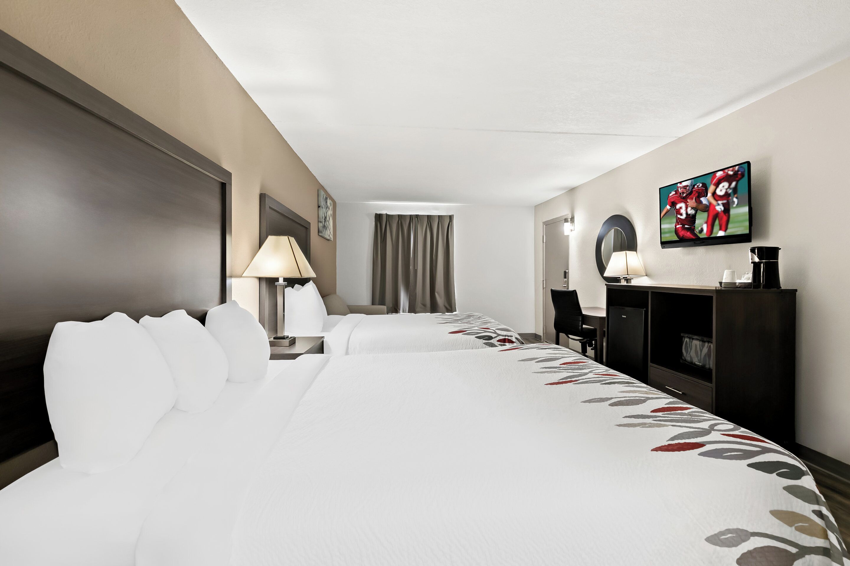A hotel room with a large bed, two bedside tables with lamps, a desk, a television, and a wardrobe.