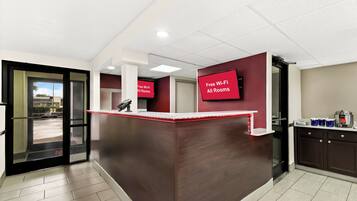 A reception area with a dark wooden counter, a glass door entrance, and a sign indicating free Wi-Fi in all rooms.