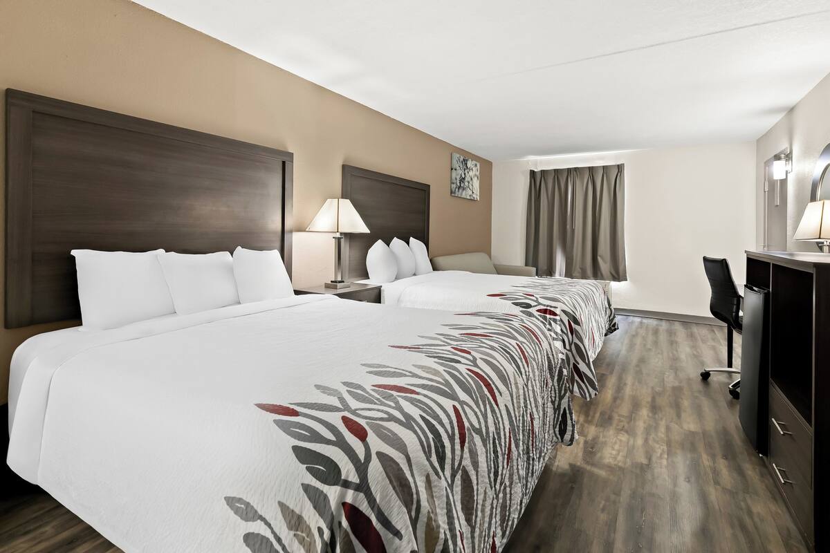 Ein Hotelzimmer mit zwei Betten, einem Schreibtisch, einem Stuhl und einem Kleiderschrank.