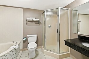 A bathroom with a glass-enclosed shower, a white toilet, a bathtub, and a black marble sink. - Red Roof Inn & Suites Duncan (Duncan)