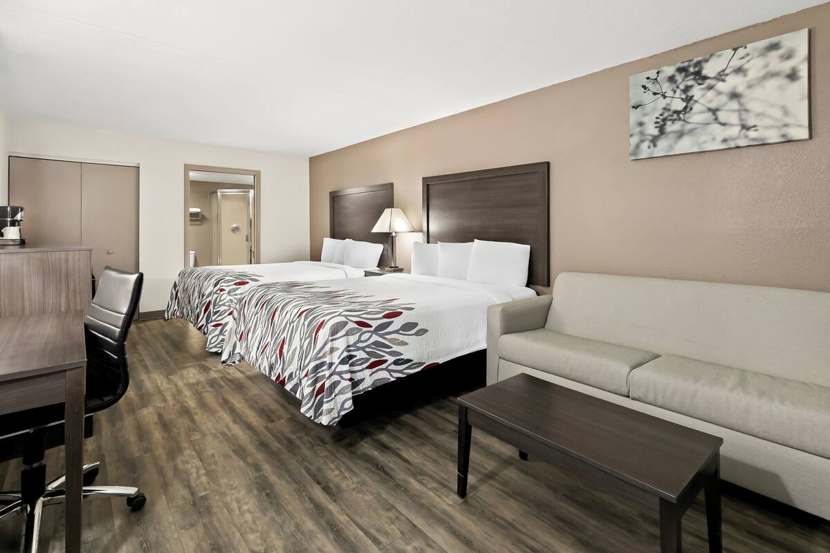 Ein Hotelzimmer mit einem großen Bett, einer Couch, einem Schreibtisch mit Stuhl und einer Kaffeemaschine.