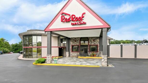 A Red Roof Inn & Suites building with a modern design, featuring a prominent red and white color scheme, large windows, and a spacious parking area. - Red Roof Inn & Suites Duncan (Duncan)