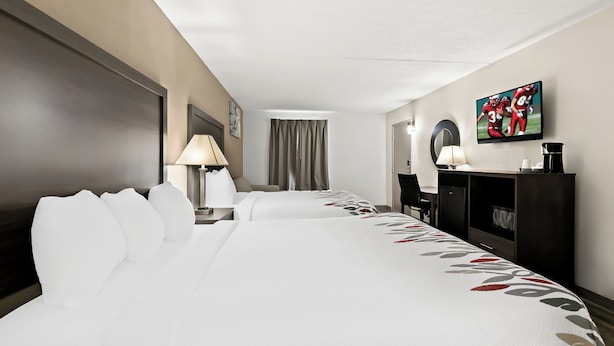 A hotel room with a large bed, two bedside tables with lamps, a desk, a television, and a wardrobe. - Red Roof Inn & Suites Duncan (Duncan)