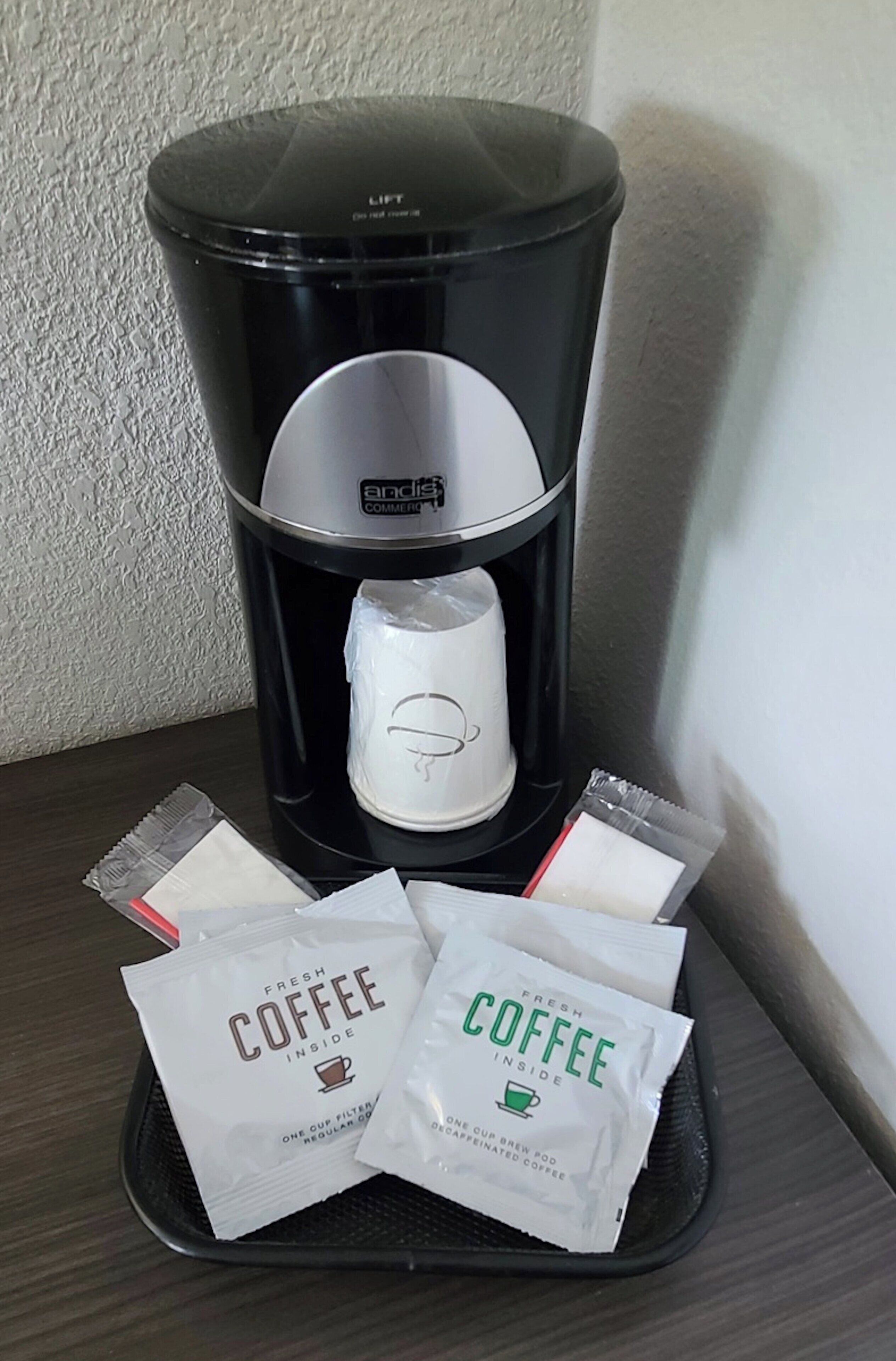 A coffee maker with a cup filter and two coffee pods on a table.