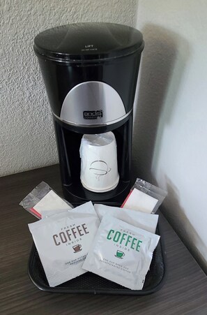 A coffee maker with a cup filter and two coffee pods on a table. - Red Roof Inn & Suites Duncan (Duncan)