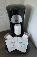 Una cafetera con un filtro para taza y dos cápsulas de café sobre una mesa.
