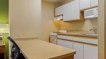 A compact kitchen with a single countertop, a microwave, a sink, and a stove.