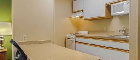 Una cocina compacta con una encimera, microondas, fregadero y cocina.