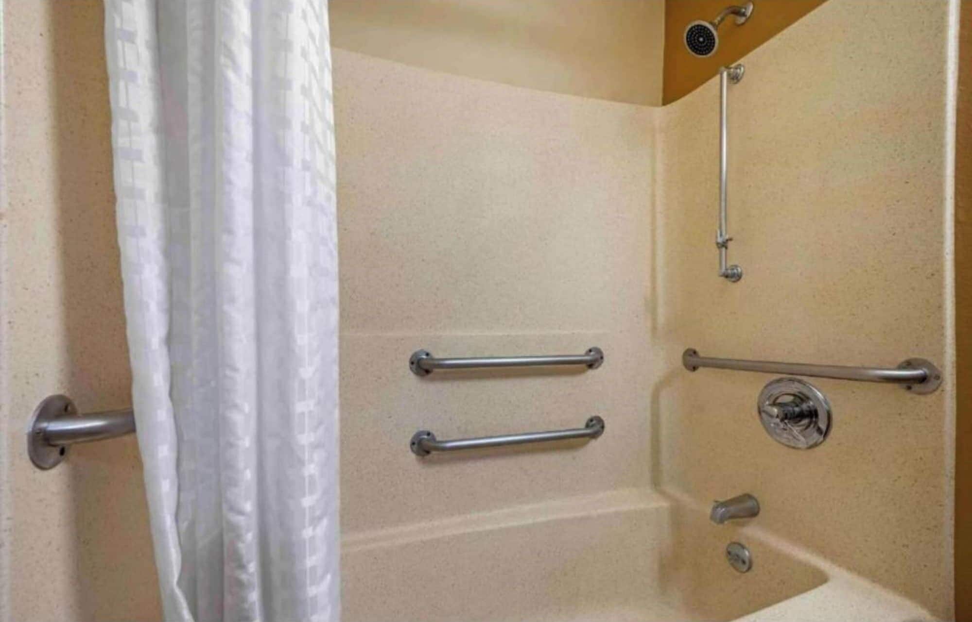 Une salle de bain équipée d’une douche, de barres d’appui et d’une baignoire.