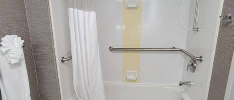 Un baño moderno con bañera, ducha y barra de apoyo.