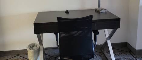 Un escritorio con una silla, un espejo y una pequeña estantería.