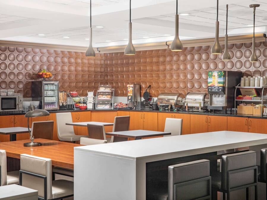 A modern cafe with a central island, seating area, and a wall with circular patterns.