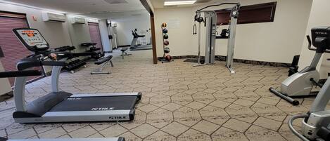 A gym with treadmills, elliptical machines, and free weights.