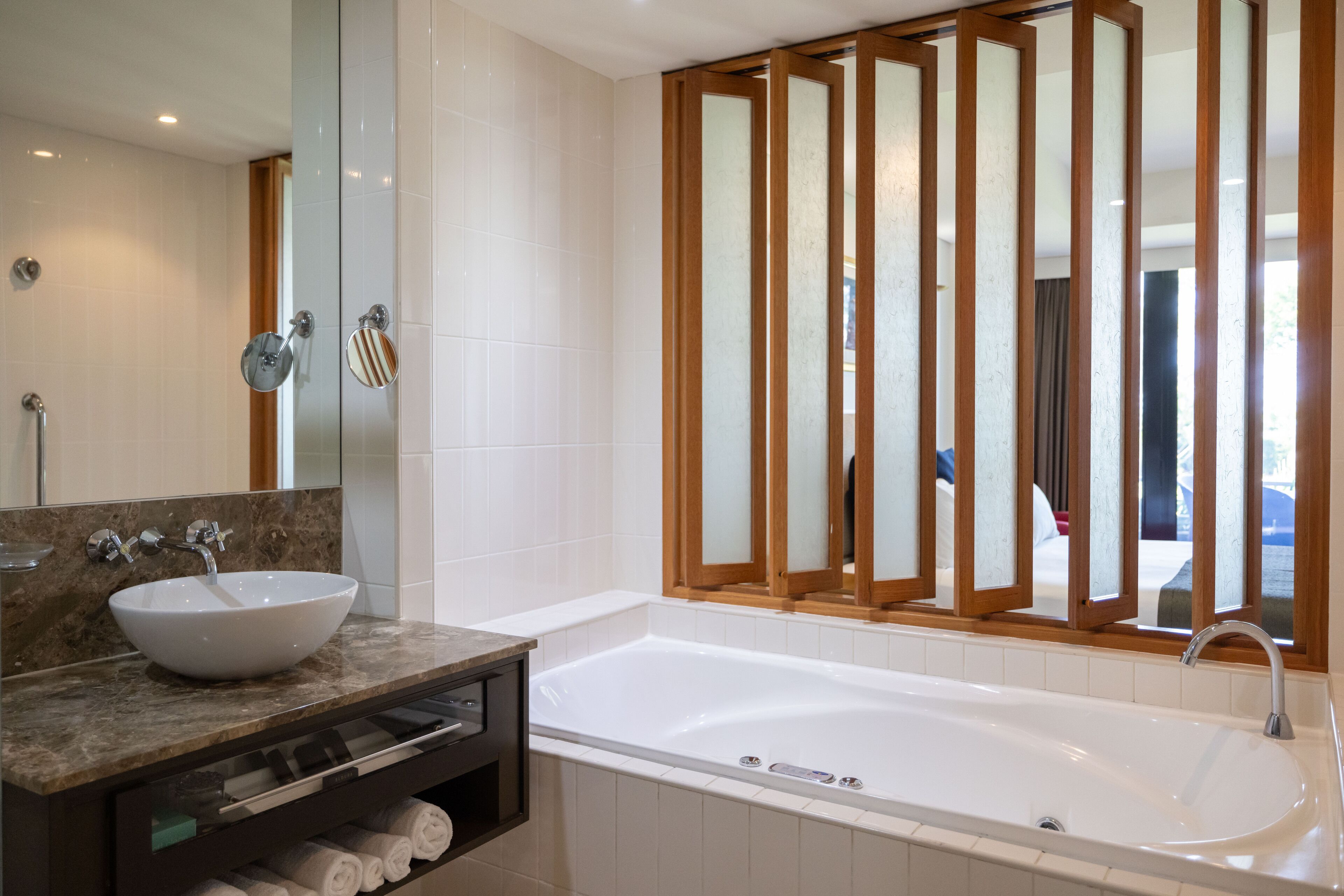 Un baño moderno con una bañera amplia, un tocador de mármol y un espejo grande.
