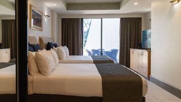 A hotel room with two beds, a TV, and a view of the outdoors.