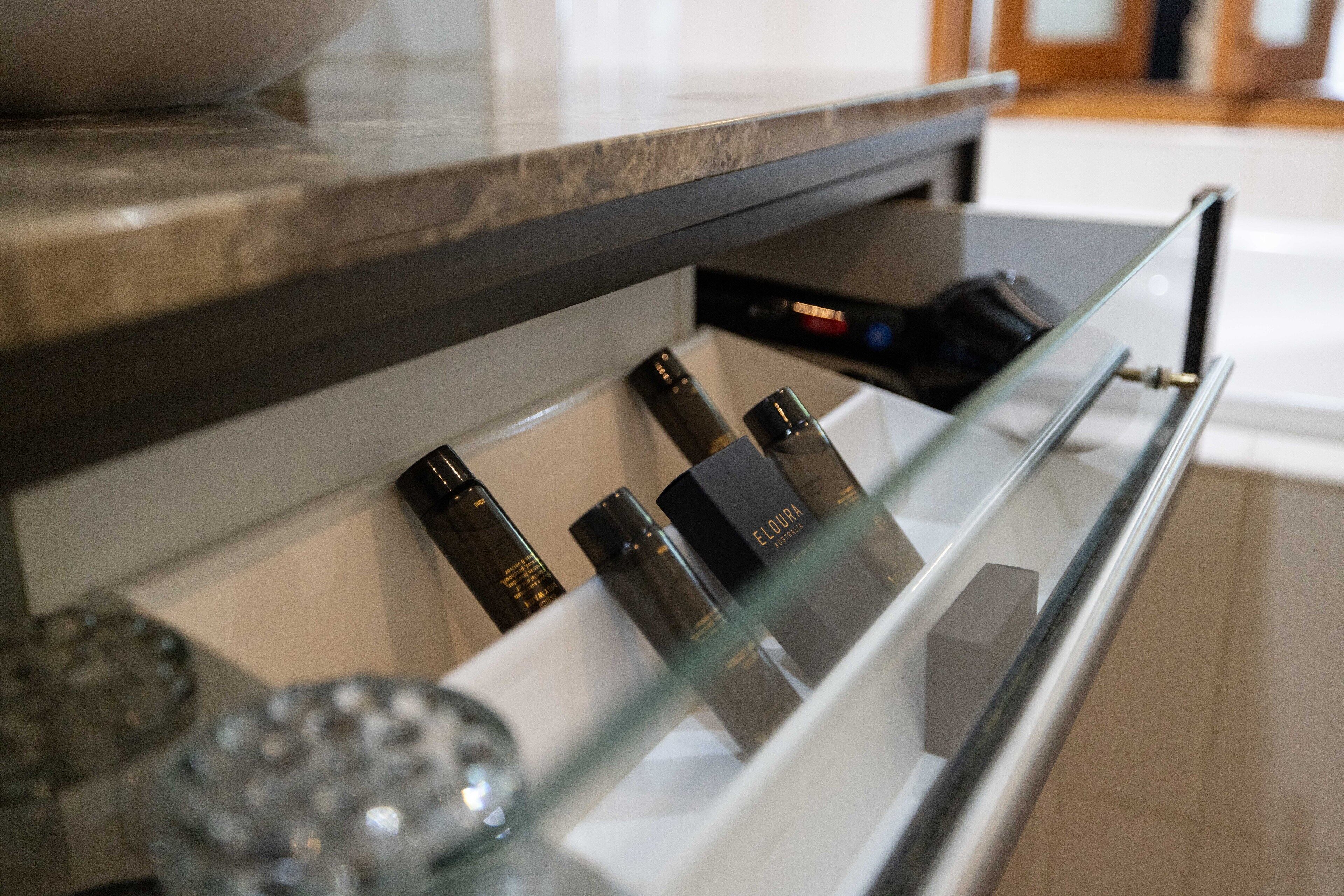 A bathroom with a glass shelf holding toiletries and a white sink.