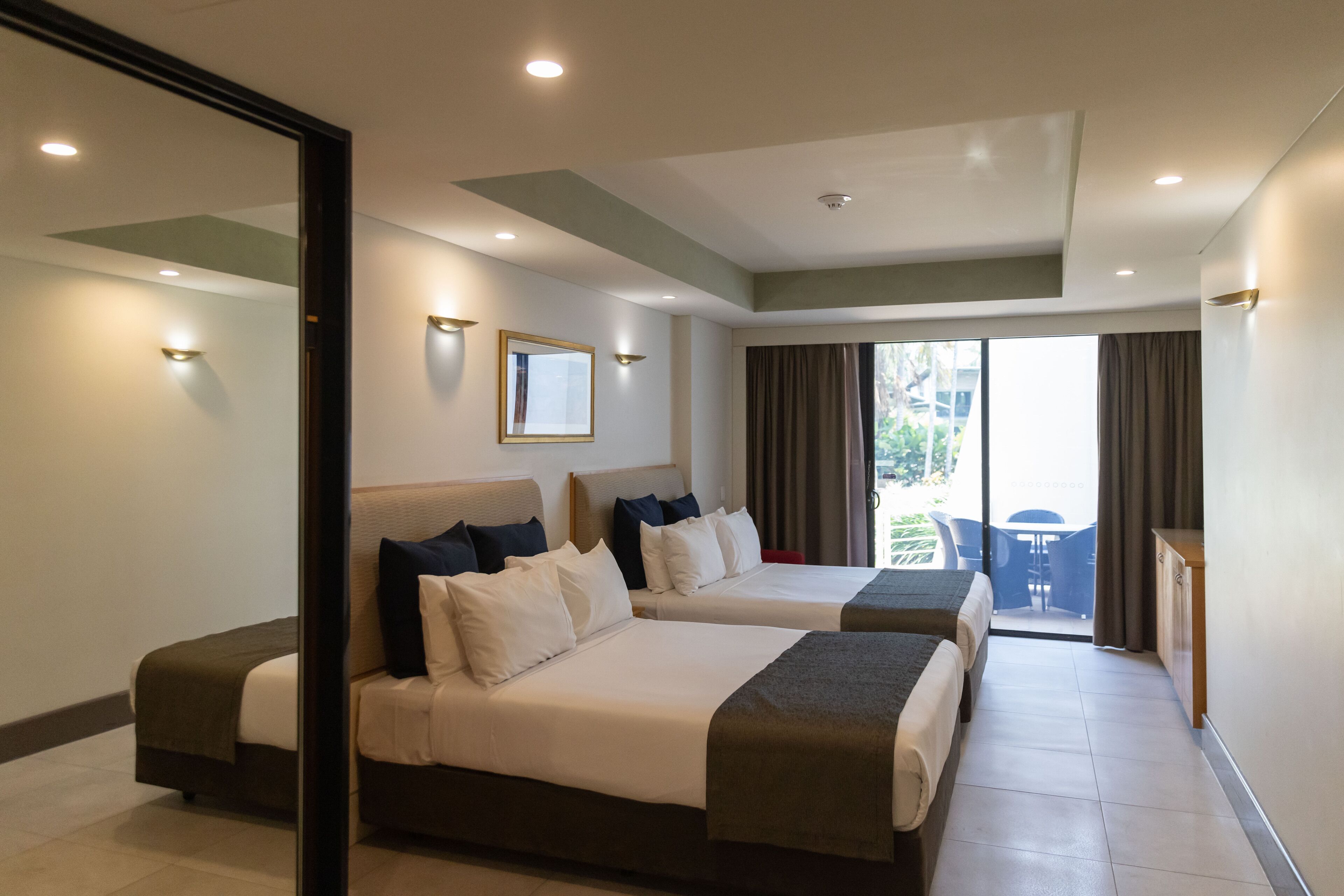Une chambre d’hôtel avec deux lits, un bureau et un balcon offrant une vue.