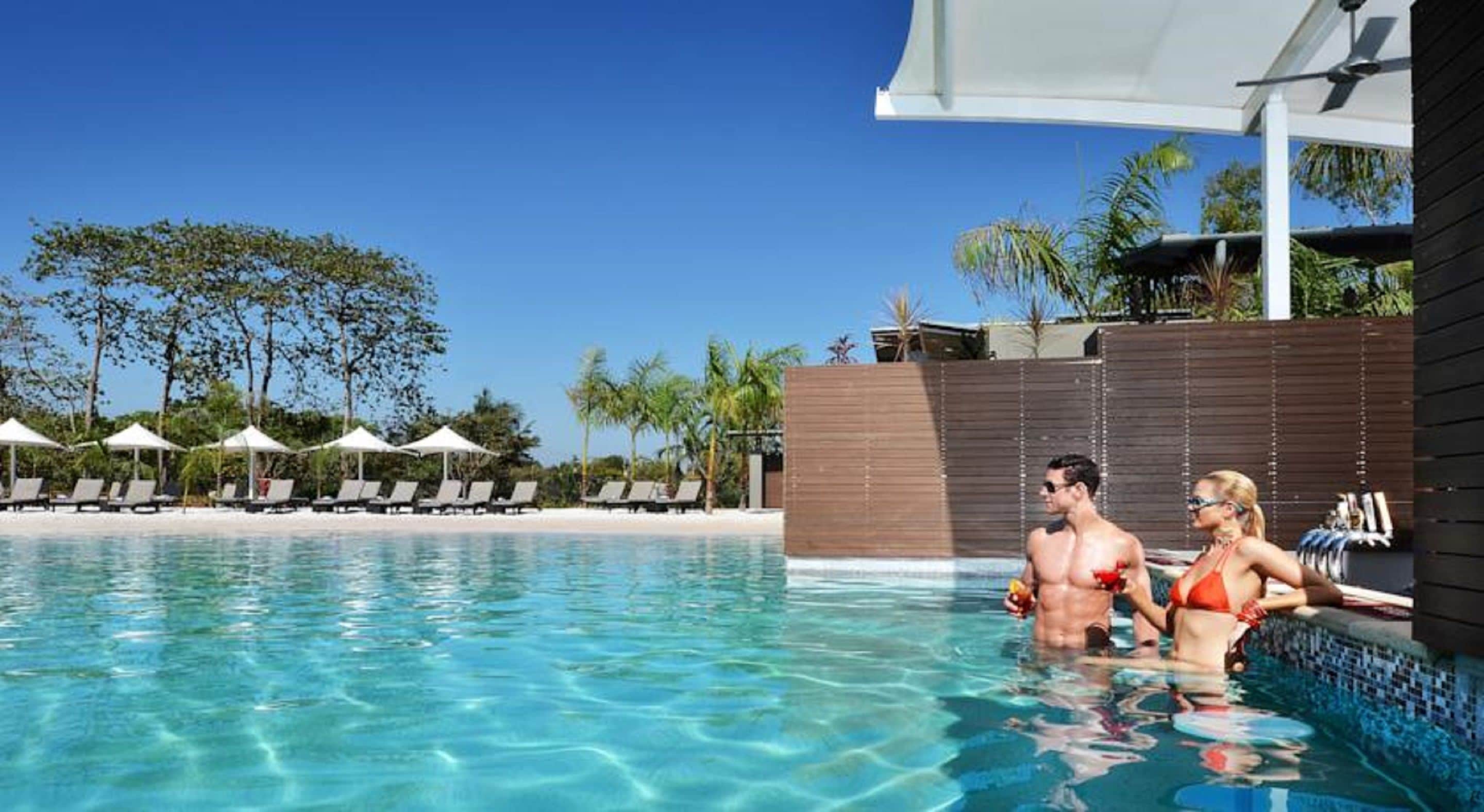 Une piscine à l’eau claire, des chaises longues et des parasols.