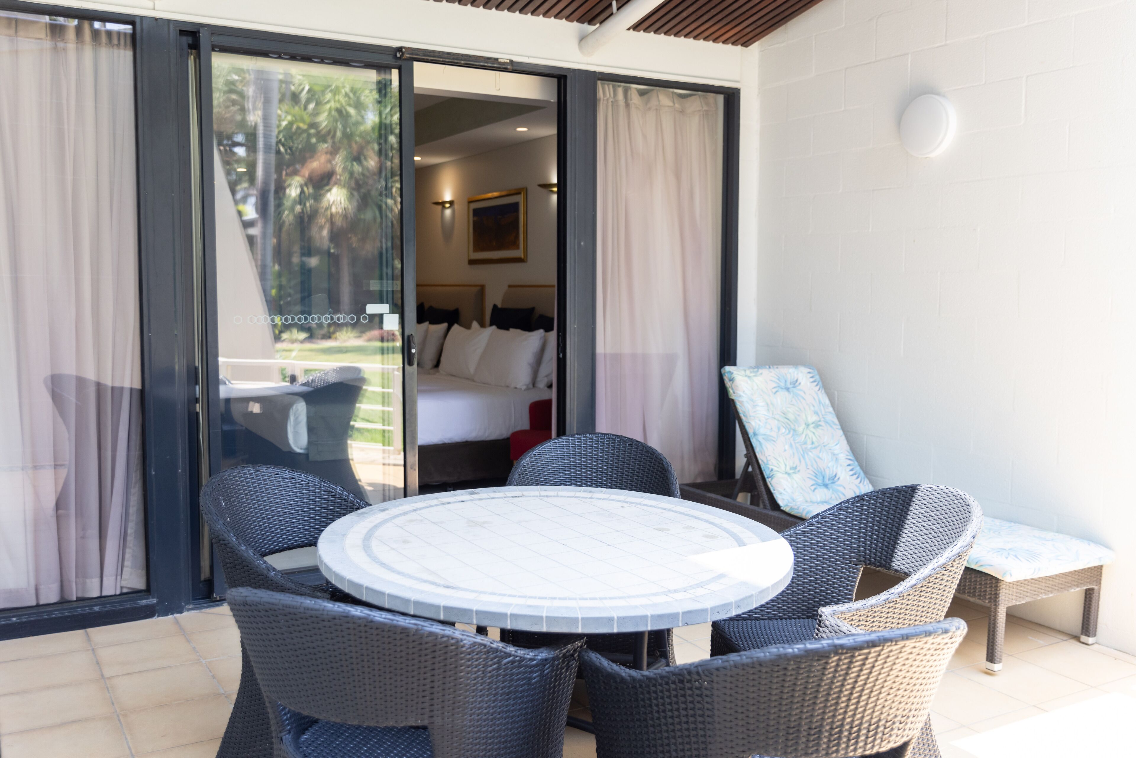 Una habitación con cama, ventana con cortinas, una mesa y sillas, y vistas al exterior.