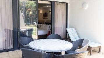 Una habitación con cama, ventana con cortinas, una mesa y sillas, y vistas al exterior.