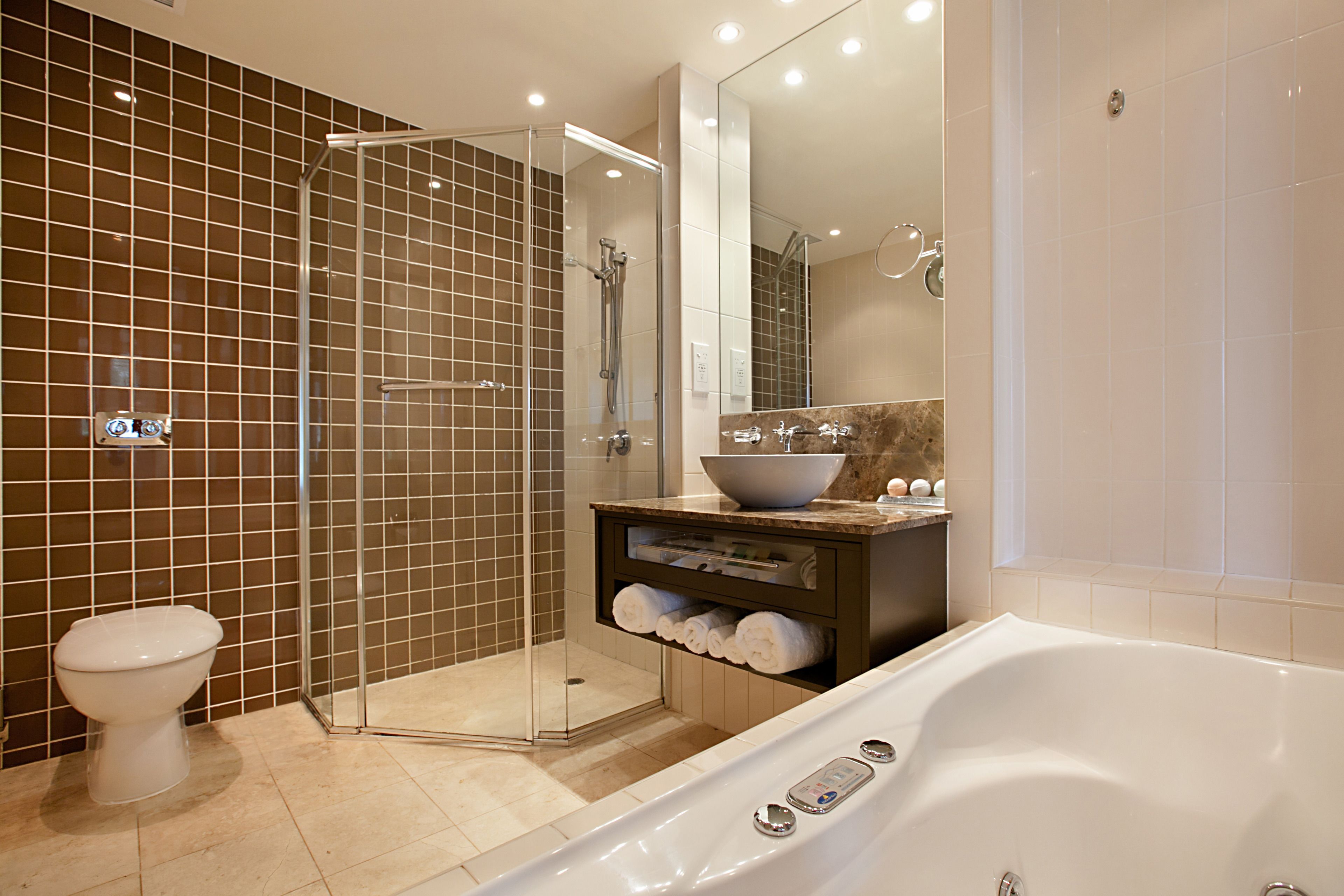 Ein modernes Badezimmer mit einer gläsernen Duschkabine, einer großzügigen Badewanne und einem Waschtisch mit einer Schüssel.