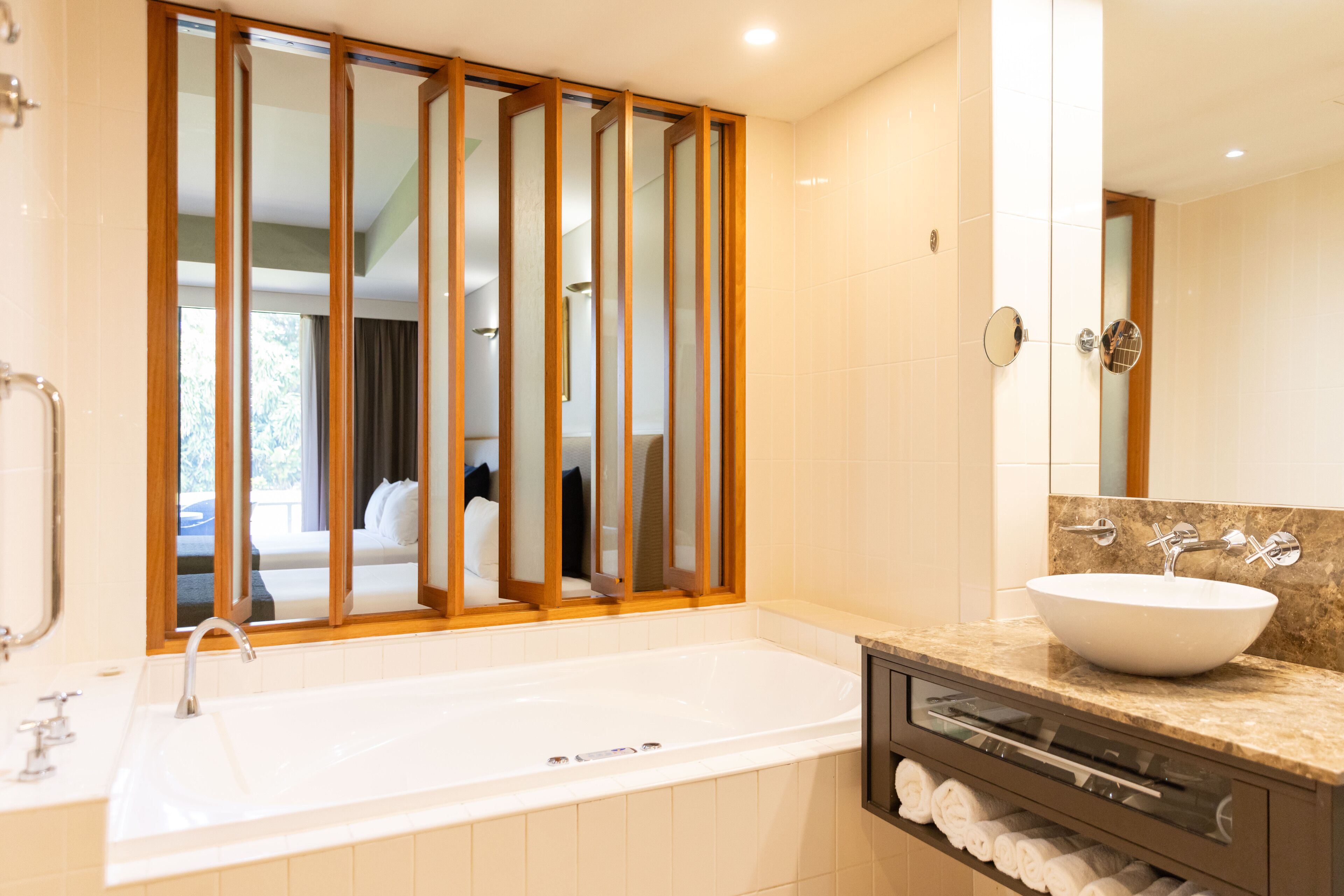 A modern bathroom with a large bathtub, a vanity with a sink, and a mirror.