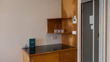 A kitchenette with a black countertop, wooden cabinets, and a wine glass holder.