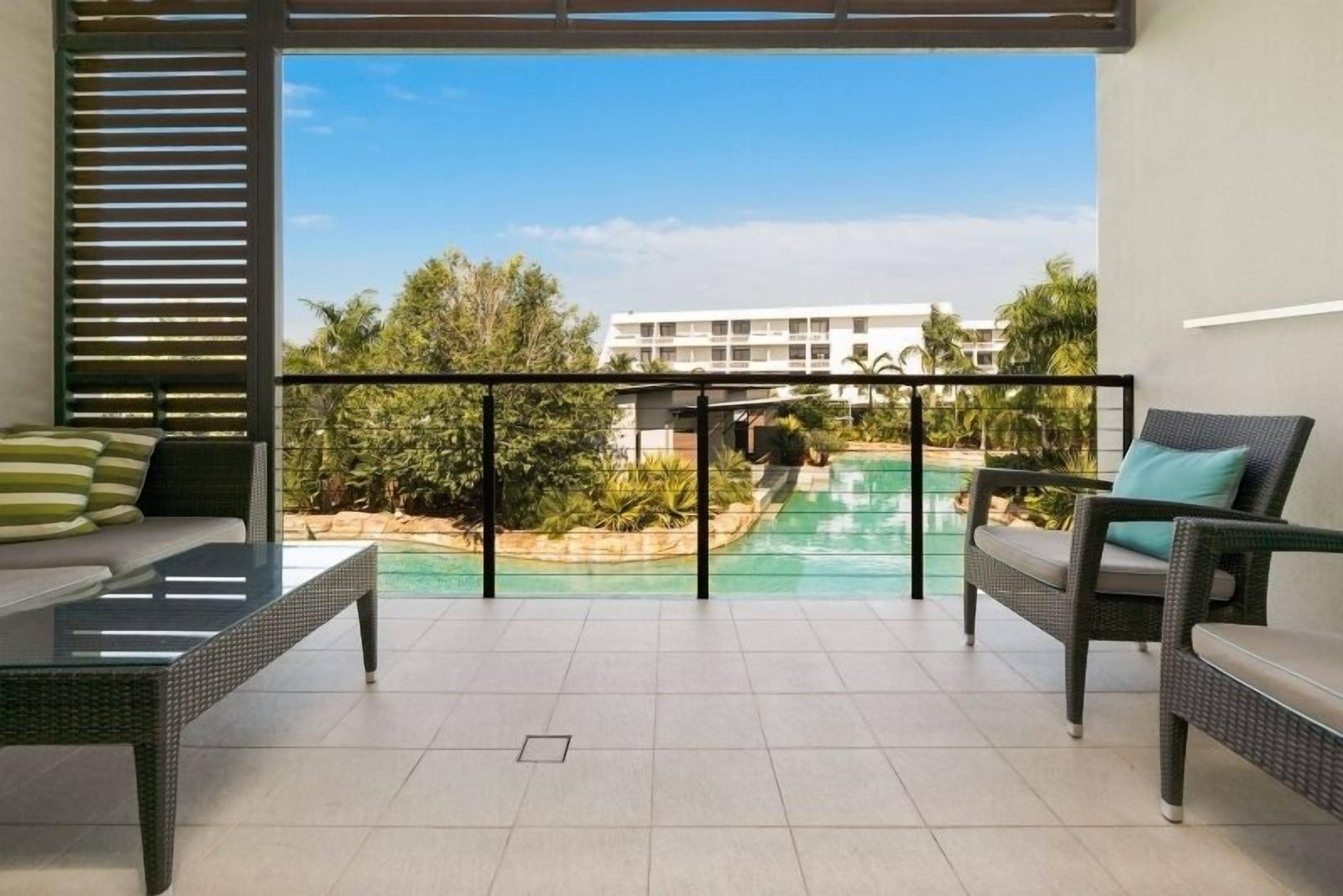 A balcony with a view of a swimming pool and a building in the background.
