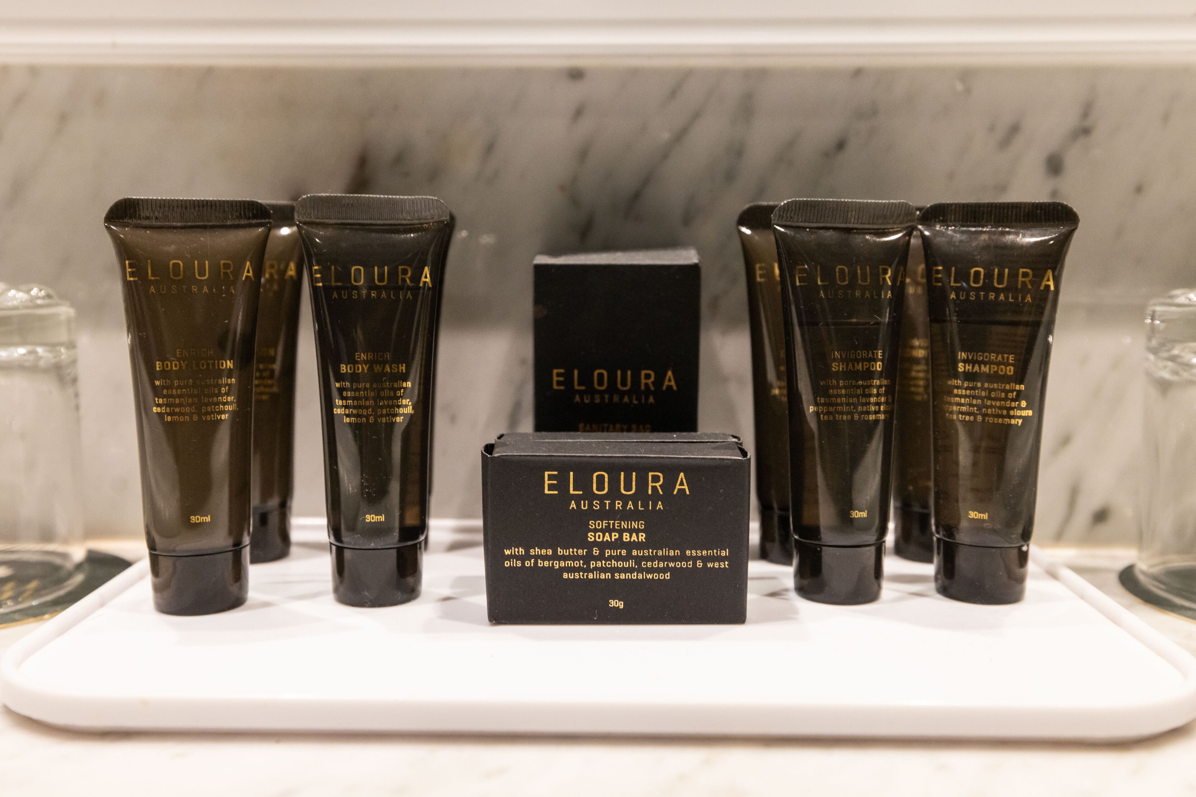 Une sélection de produits de soins corporels de la marque ELOURA Australia, présentée sur un plateau blanc.