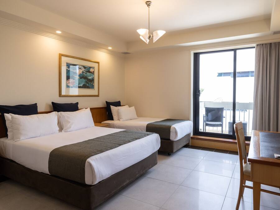 A hotel room with two beds, a dining table, and a large window with a view.