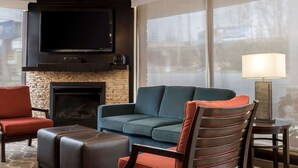 Una sala de estar moderna con un televisor de pantalla plana, chimenea, sofá y sillón.