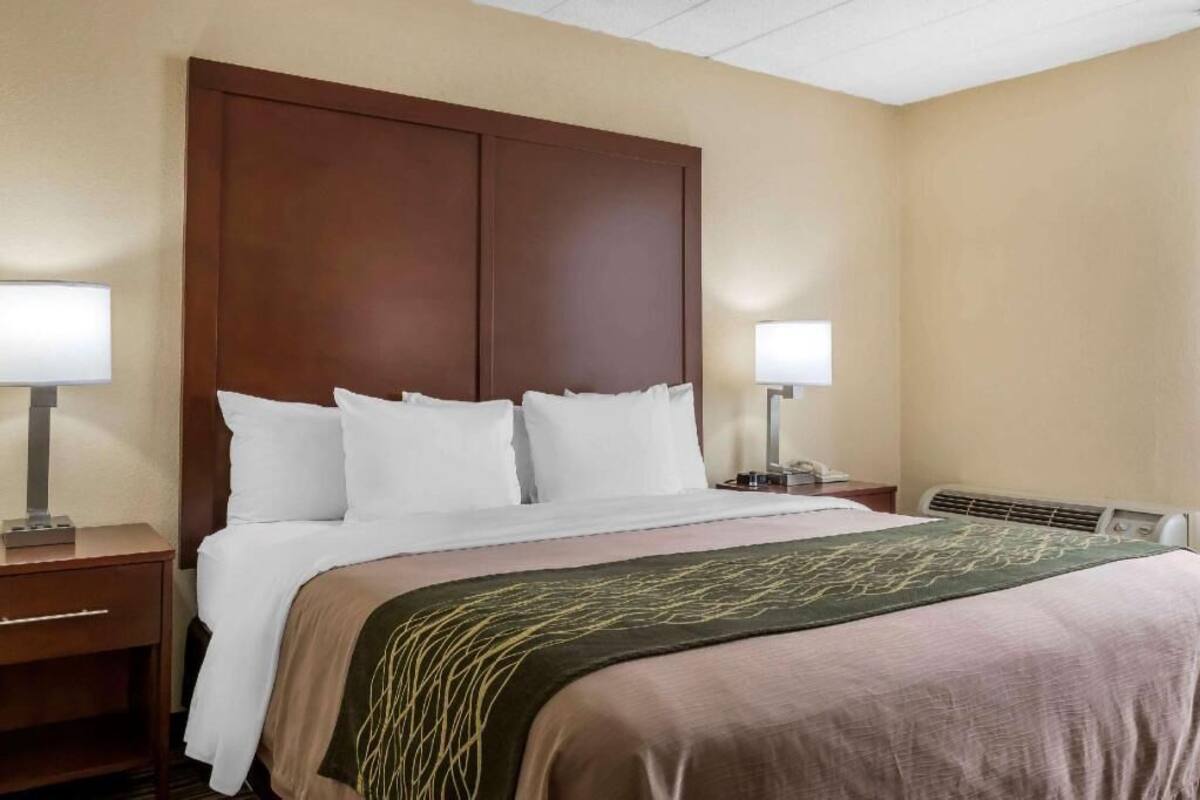Habitación de hotel con una cama grande, dos mesitas de noche, un radiador en la pared y una ventana.