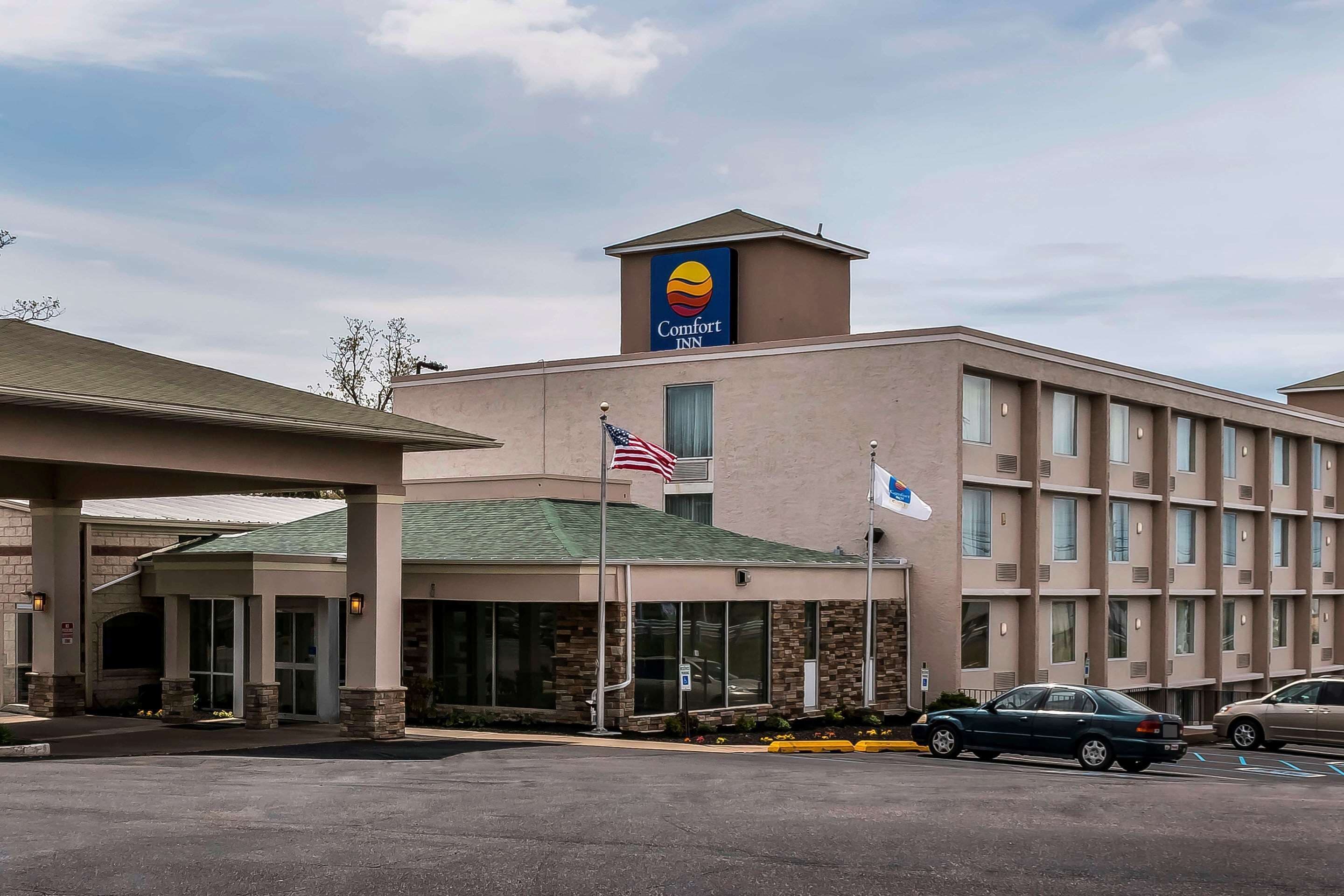 A Comfort Inn hotel with a prominent sign, an American flag, and a parking lot with cars.