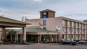 A Comfort Inn hotel with a prominent sign, an American flag, and a parking lot with cars.