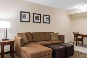 Una sala de estar moderna con un sofá seccional, una mesita redonda y una mesa de comedor con sillas. Hay tres cuadros en la pared.