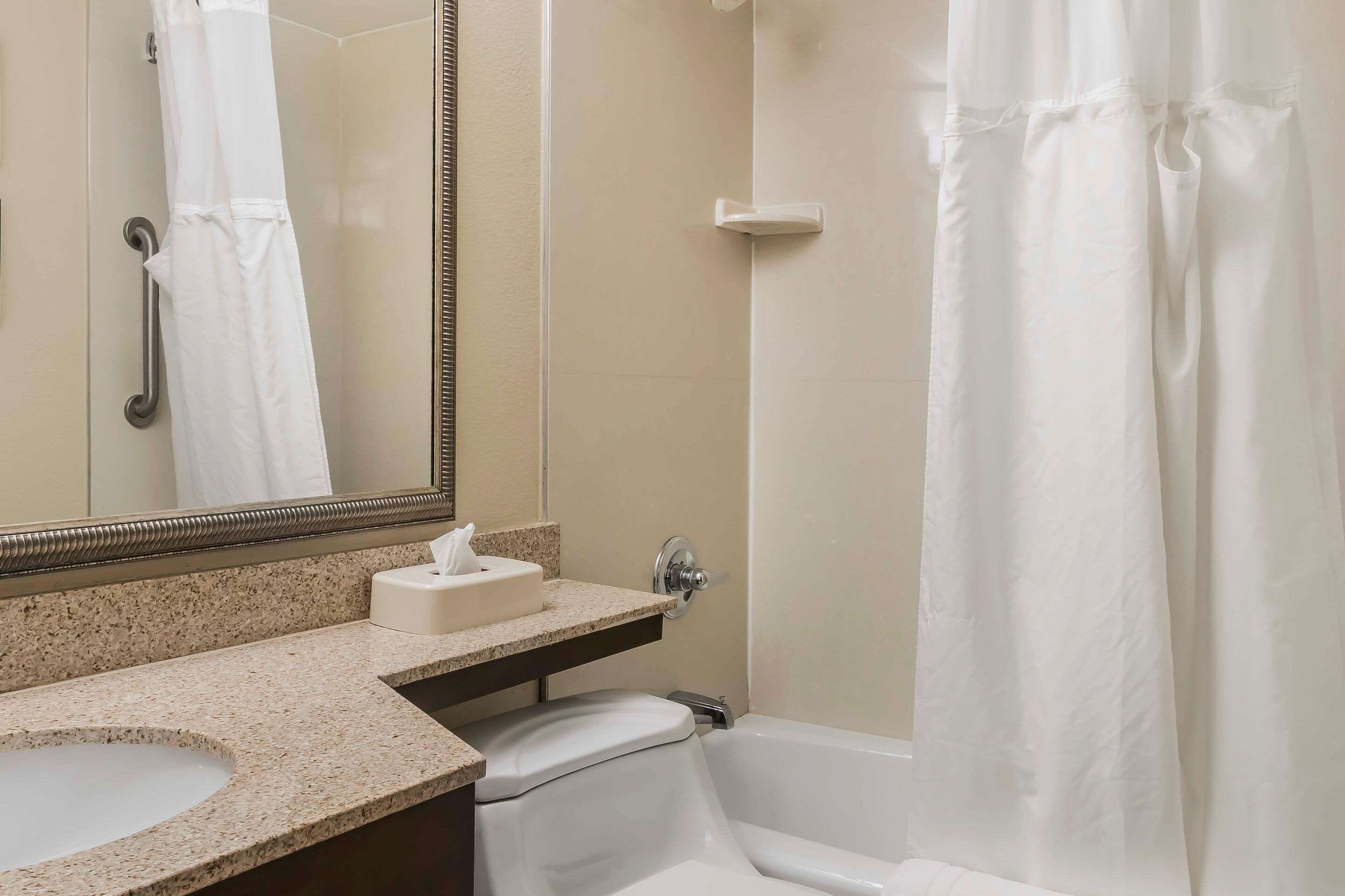 A bathroom with a sink, mirror, toilet, and bathtub.