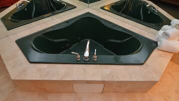 A large, modern bathtub with a glass enclosure and multiple faucets.