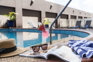Una piscina al aire libre, sillones reclinables de piscina