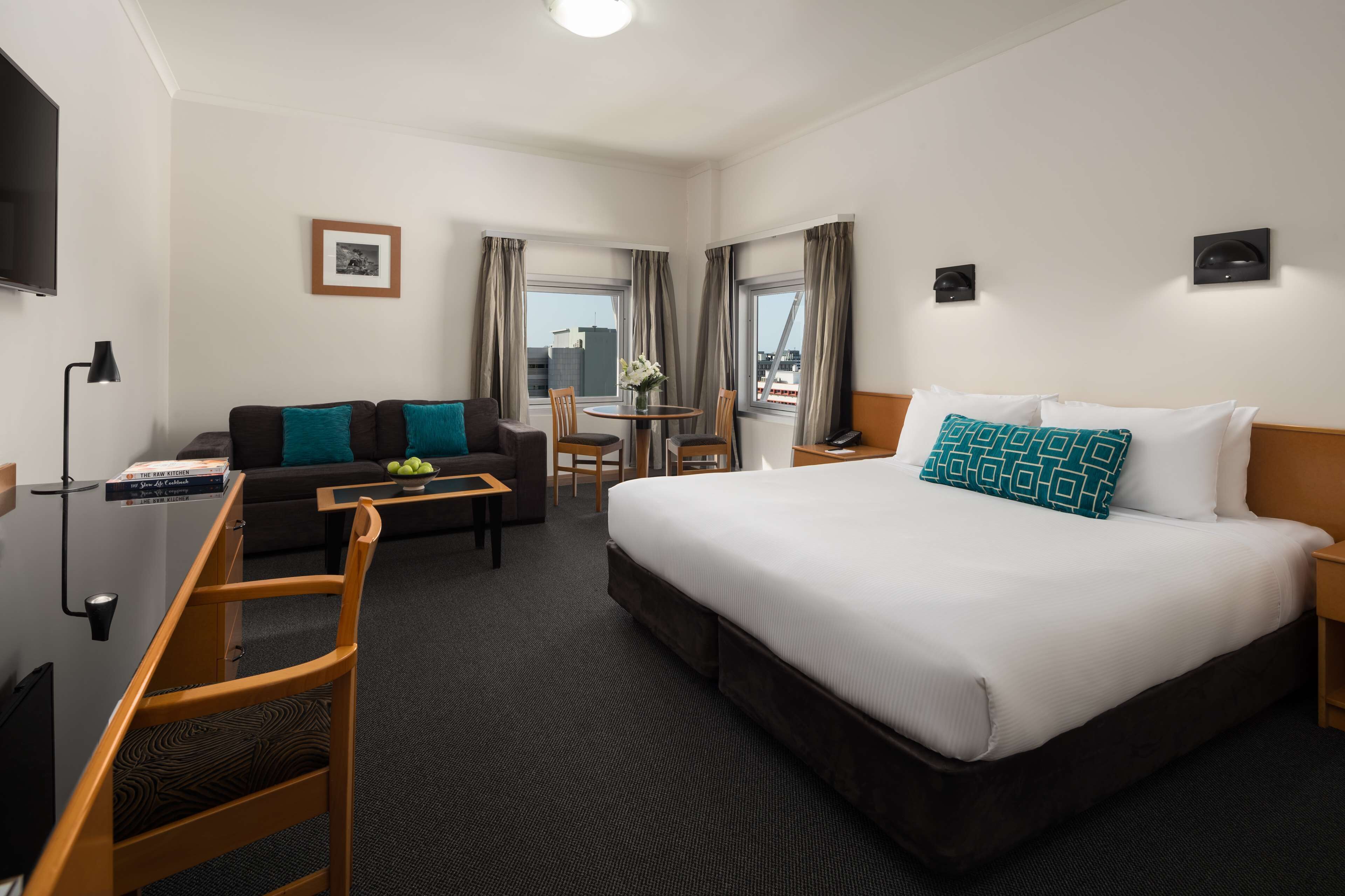 Ein Hotelzimmer mit Bett, Sofa, Schreibtisch und Fernseher.