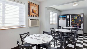 A cafe with round tables and chairs, a vending machine, and a wall with a motivational quote. - Super 8 by Wyndham Johnson City (Johnson City)
